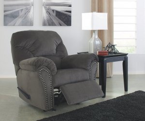 Gray kinlock recliner with nailhead accecents next to a side table with a lamp. Above recliner is a wall canvas of a dock overlooking the water.