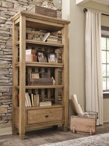 light brown wood open faced bookcase with four shelves and storage drawer holding magazines and books and other keepsakes.