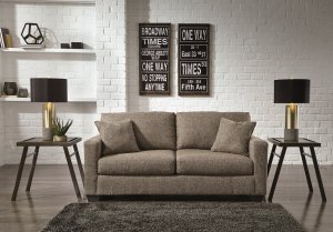 Ash colored sofa in a plain white room with a white brick wall and gray rug on the floor with two modern side table next to it.