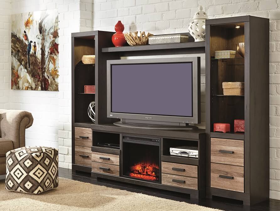 Black entertainment center staged with home decor pieces with drawers along the bottom in a room with a rug and a pouf