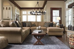 Ultra plush cushions and traditional styling, this sectional is cozy and classic. It is in a large living room setting with a blue rug and chandelier hanging above.