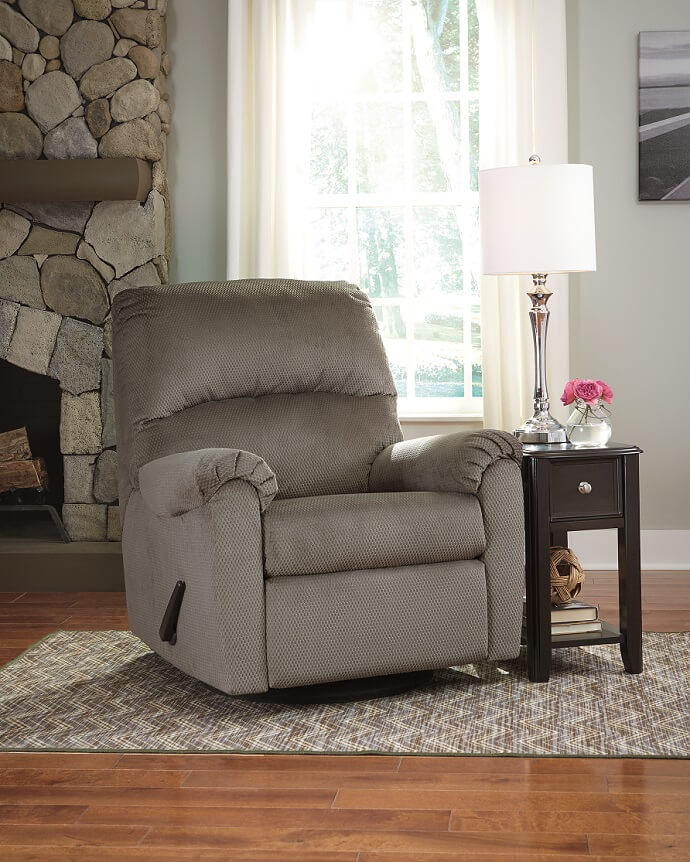 gray recliner in a room with one window and side table with a lamp on it.