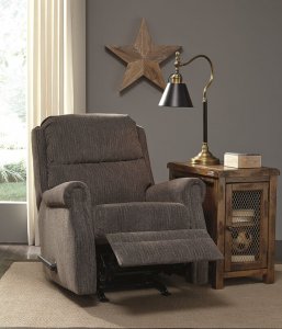 Reclining chair with gray fabric construction in a room with a rustic star on the wall with a wooden side table on the side of the recliner.