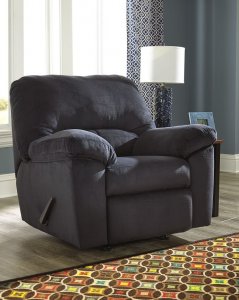 blue recliner in a room with one window and a side table with a lamp on it.