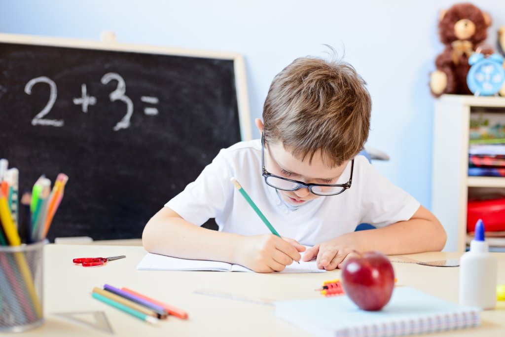 7 years old boy solves multiplication table in his copybook.