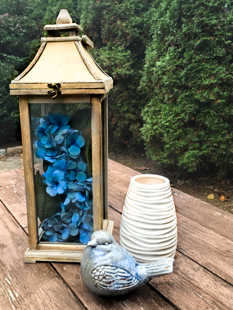 Lantern filled with faux flowers for an outdoor spring decoration.