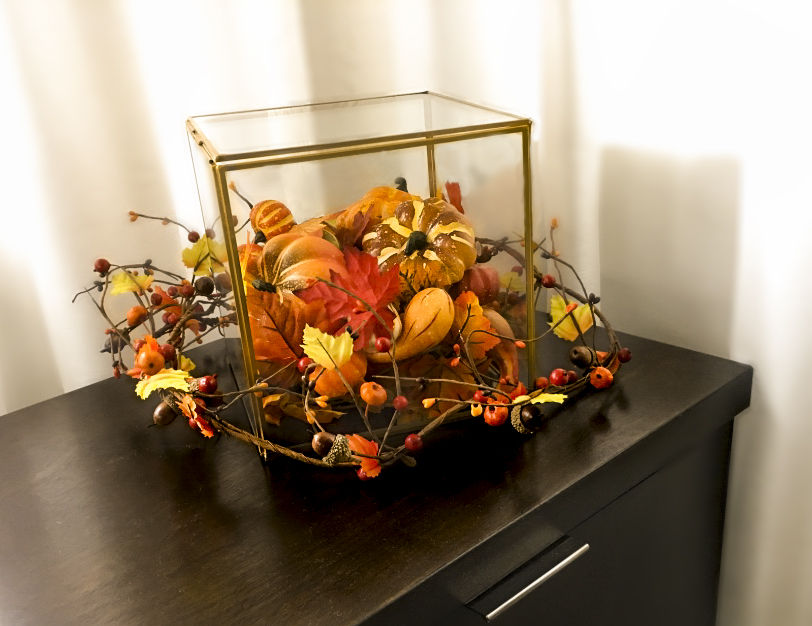 Decorative fall glass box filled with fall decorations like leaves, pumpkins, and garland.