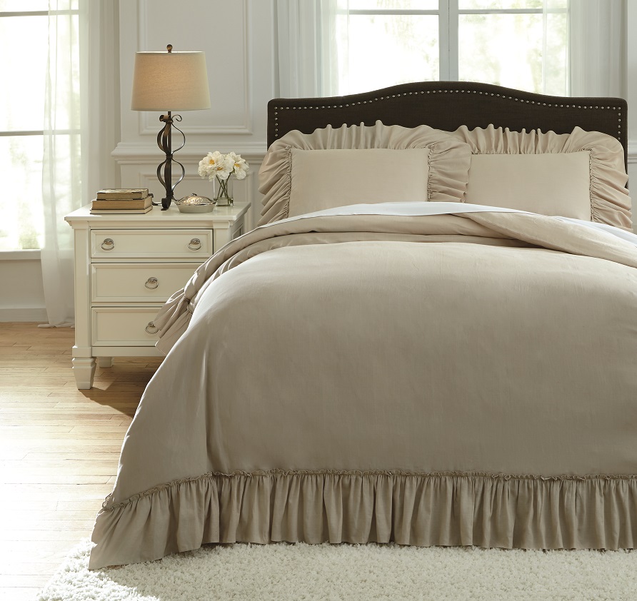 Farmhouse chic bedding in a neutral room with white nightstands and drapes.