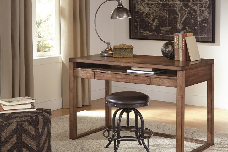 Baybrin modern contemporary rectangular wood desk with black swivel stool and gray and black striped pouf on the ground. Infront of the desk is a framed map.