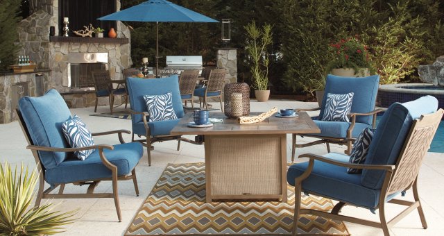 Outdoor dining set with a firepit, chairs and an outdoor kitchen in the background.