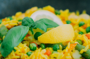 Chicken Paella made with yellow rice, vegetables and garnished with lemon slices.