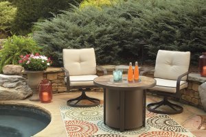 outdoor patio tile table with beige chairs with blue cushions, underneath is a blue and green chevron rug