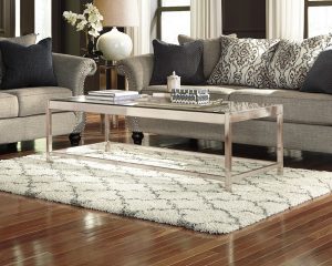 white and gray gate rug underneath a silver coffee table.