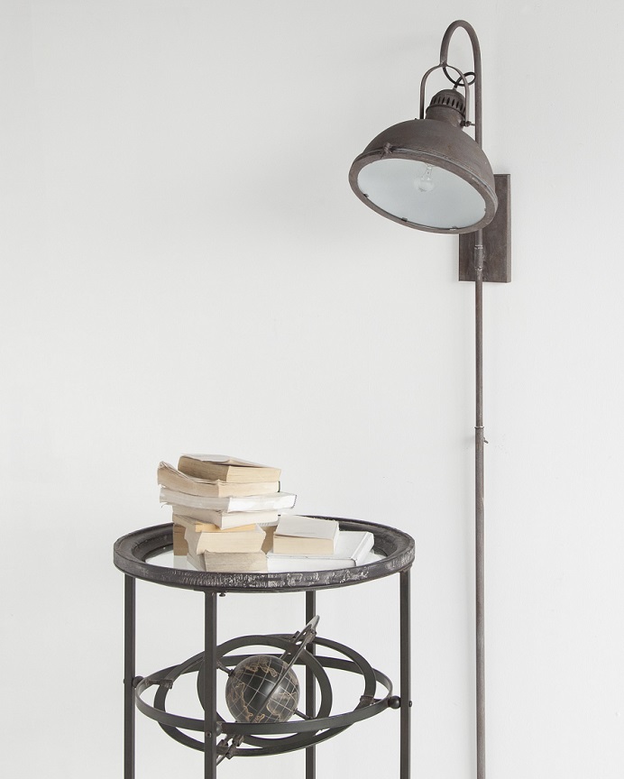 An antique looking brown wall light is ready next to a table with a pile of books