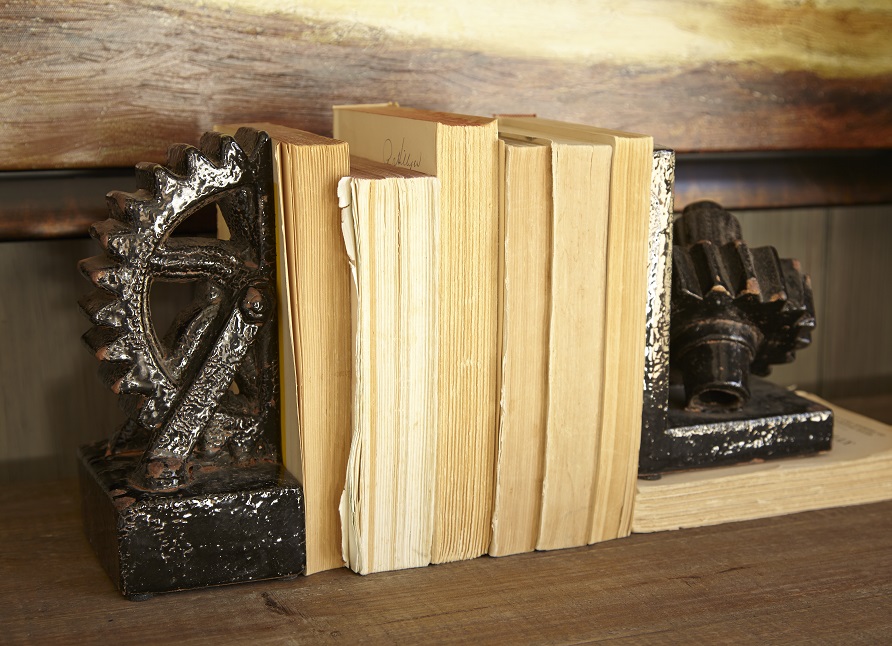 Set of two interesting bookends shaped like gears with books in between them on a table. 