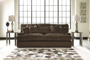 Neutral colored polka dotted rug in front of a brown plush sofa.