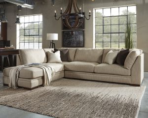 Ashley sectional in a large room with 2 large windows with a rug in the center of the room and a chandelier hung above.