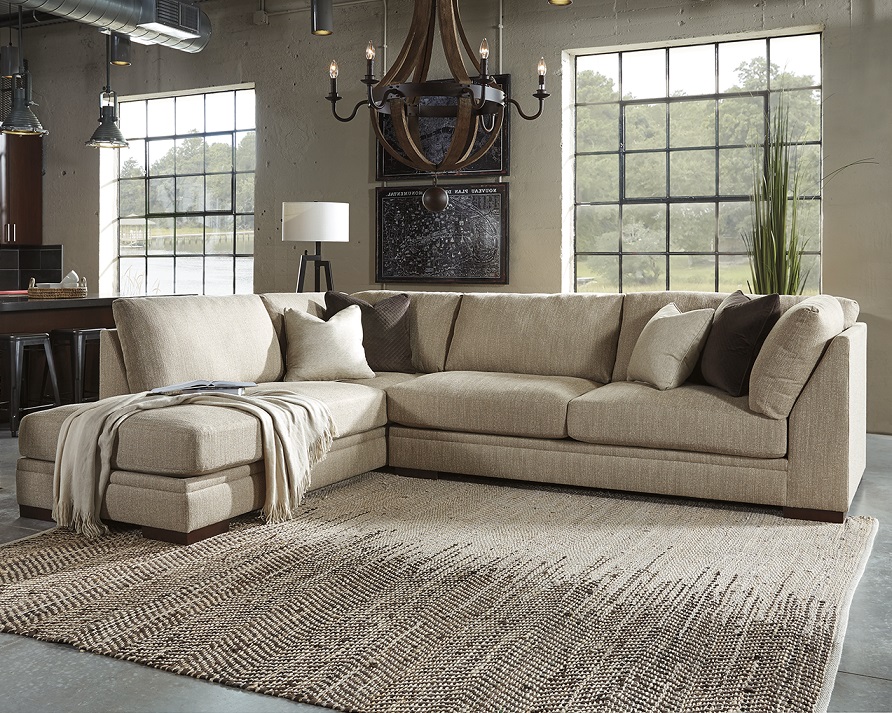Ashley sectional in a large room with 2 large windows with a rug in the center of the room and a chandelier hung above. 