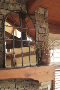 arched window design mirror on a rustic mantel.