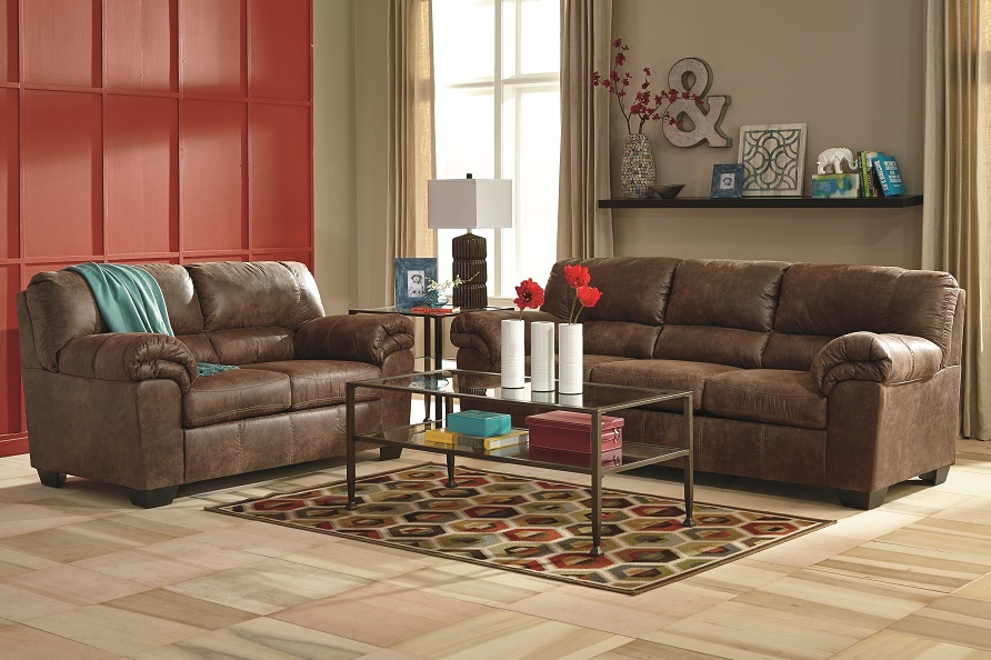 The leather bladen sofa and loveseat in a simple living room setting with a red wall and complimentary accessories throughout. 