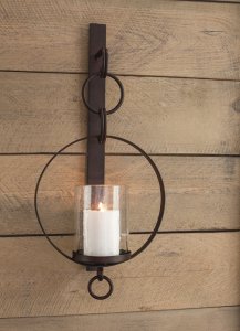 antique brown metal chain link designed wall sconce with a candle in it hanging on a wood panel wall.