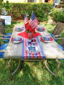 Red white and blue jean dining table set up in the backyard.