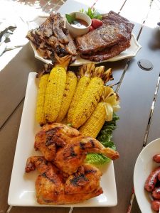 A variety of food from the grill including corn, steak and chicken.
