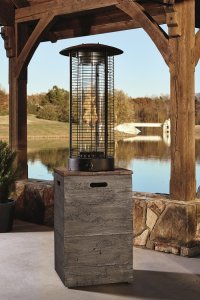 An unlit brown and gray patio heater in front of a lake.