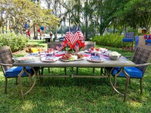 Outdoor dining table and chairs set with all kinds of food with memorial day decor.