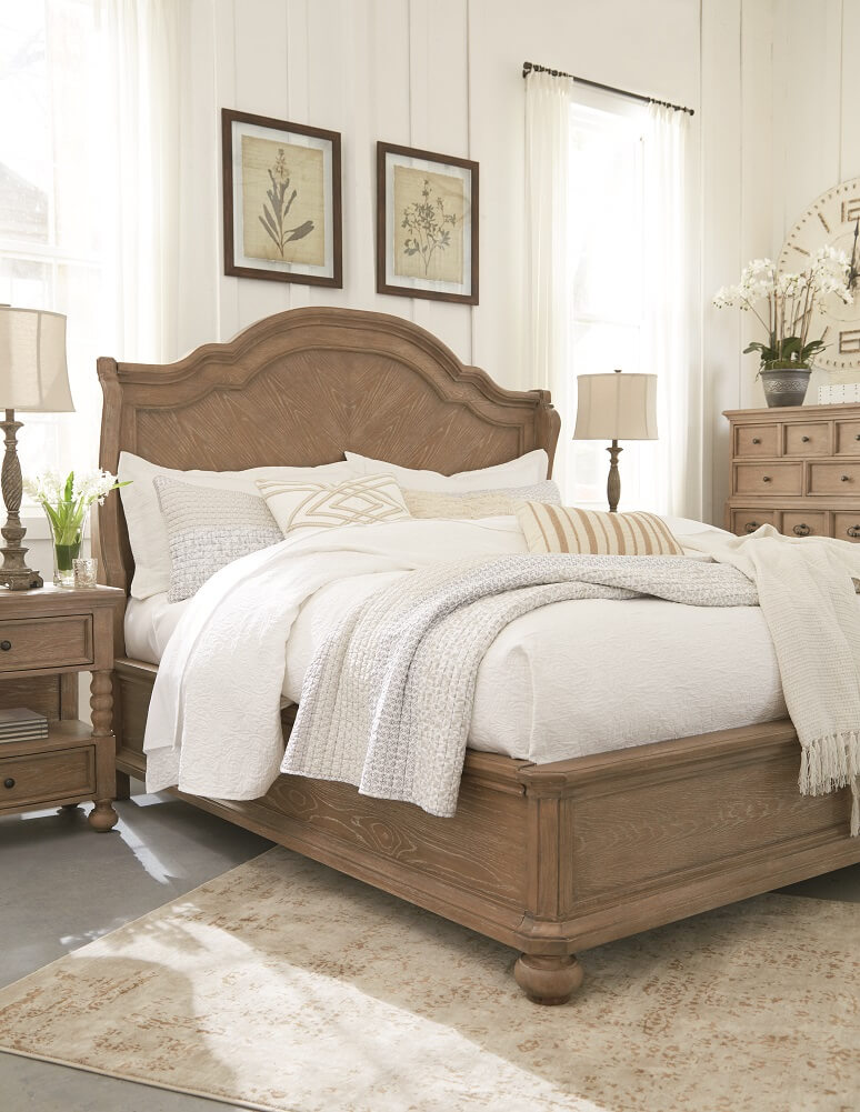 Large light brown bed with white bedding in a very natural well lit setting.
