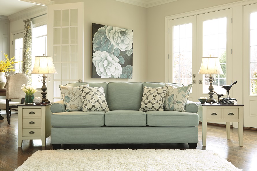 Seafoam green sofa in a white room with matching coastal decor.