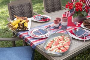 Outdoor dining table set with barbecue foods and 4th of july decorations.