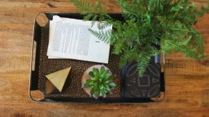 bohemmian tray with books, greenery and sculptures.