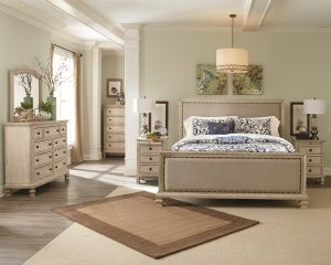 Farmhouse chic befroom with bed, dressar and nightstand with rustic artwork and a neutral rug.