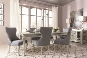 Gray sleek and glamorous dining room table with a gray and white patterned rug.