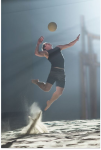 image of a professional volleyball player in the sand spiking the ball.