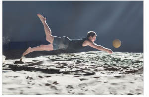 Professional Volleyball player diving for a ball on a beach volleyball court.