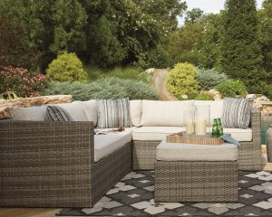 Outdoor sectional with matching pillows and table in a garden.