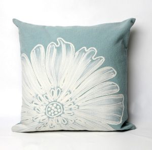 Light blue pillow with a white flower printed on it.