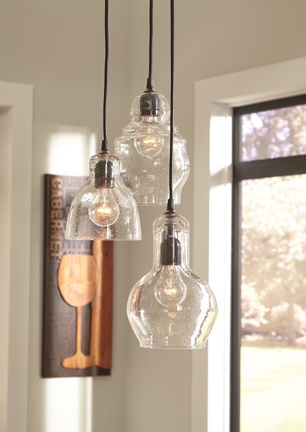Light fixture trio of seeded glass pendants with eclectic shapes hanging from the ceiling. 