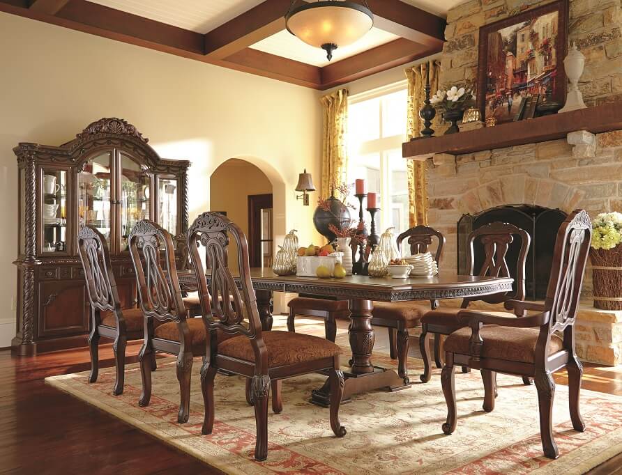 Formal dining room and chairs with intricate details in the wood in a rustic like setting. 