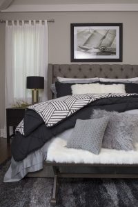 Nautical and coastal decorated bedroom with fluffy pillows, blue and gray colors and lots of accessories.