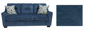 Blue sofa with aztec designed pillows with a fabric splotch next to it.