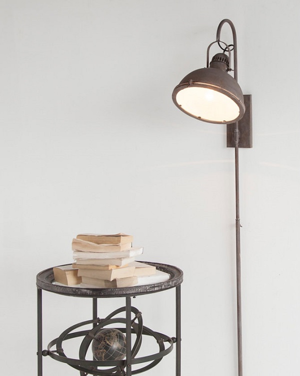 Industrial mounted lamp on a wall shining down on a side table. 