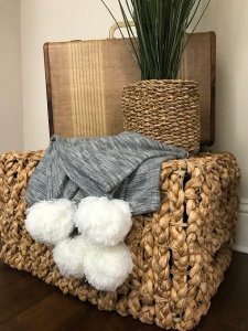 brown basket with a throw blanket holding working items.