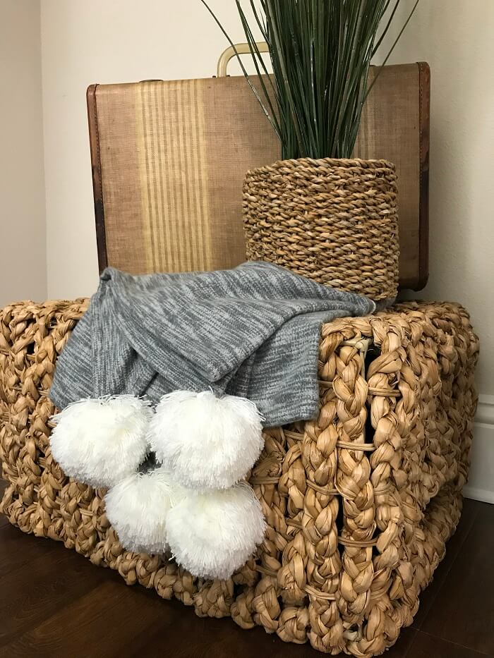 brown basket with a throw blanket holding working items. 