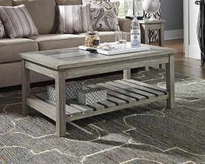 whitewashed wood coffee table with decor on top.