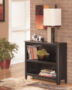 small dark brown bookcase with a lamp on top and books in the shelves