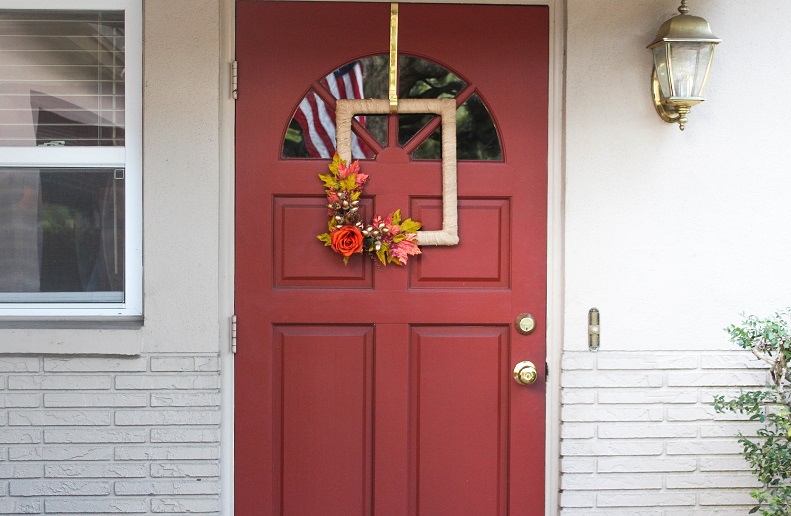 Square fall wreath on the front of a red door.