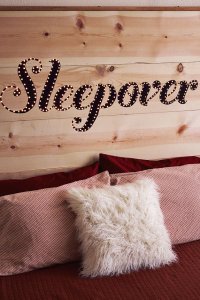 A wooden headboard with the word "sleepover" on it that lights up.